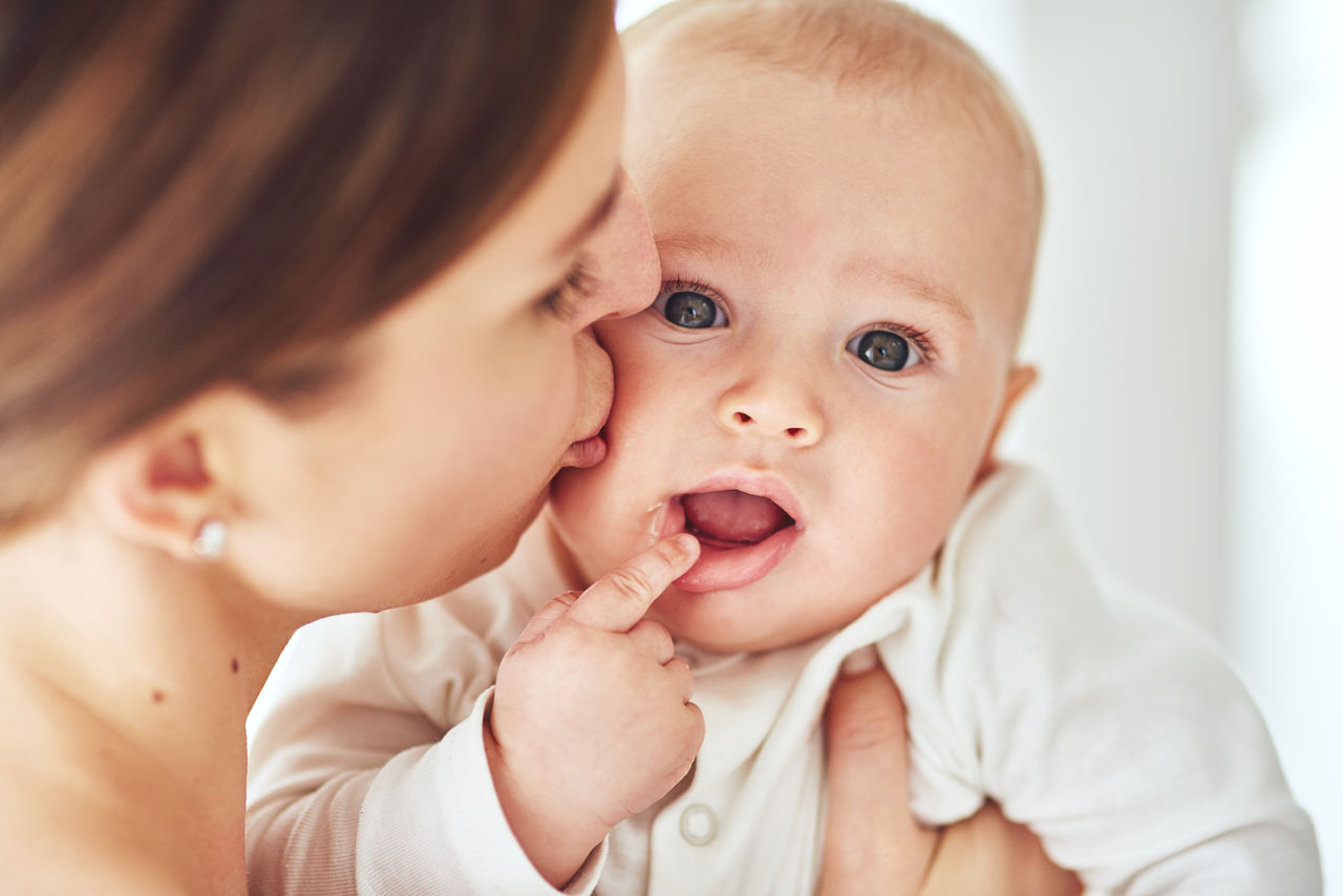 Woman checking temperature of infant formula at table indoors, closeup. Baby milk